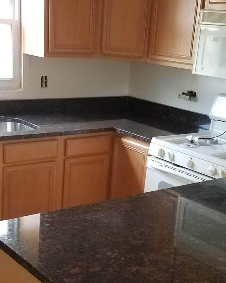 Kitchen counter with a four inch granite backsplash: a short lip of the same dark granite runs along the wall behind the counter, with painted wall above it